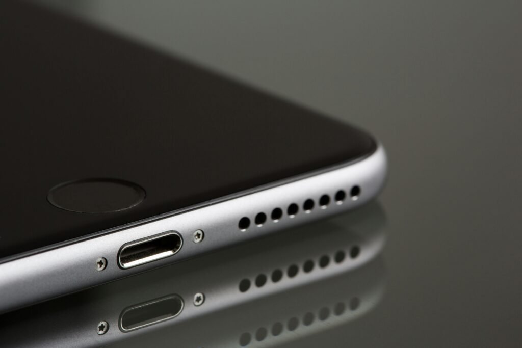 Close-up of a smartphone’s charging port and speaker grill on a reflective surface